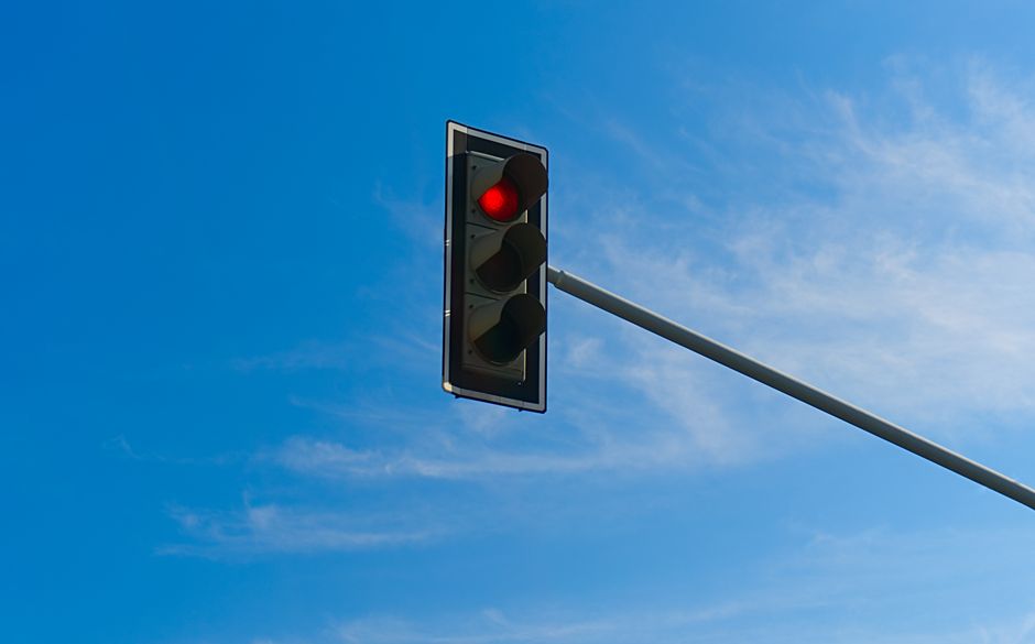 Traffic signal on red light with clear blue sky background.